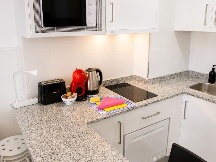 Cocina moderna equipada con cafetera, vitrocerámica y espacio funcional para una estancia cómoda.