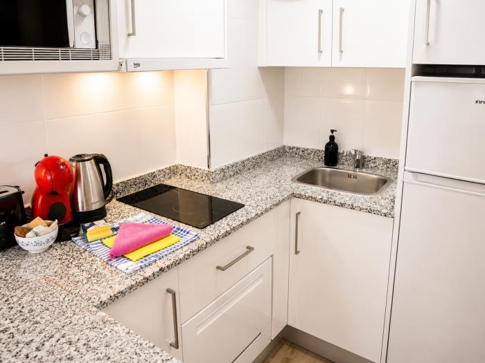Cocina moderna equipada con vitrocerámica, cafetera y espacio funcional para una estancia cómoda.