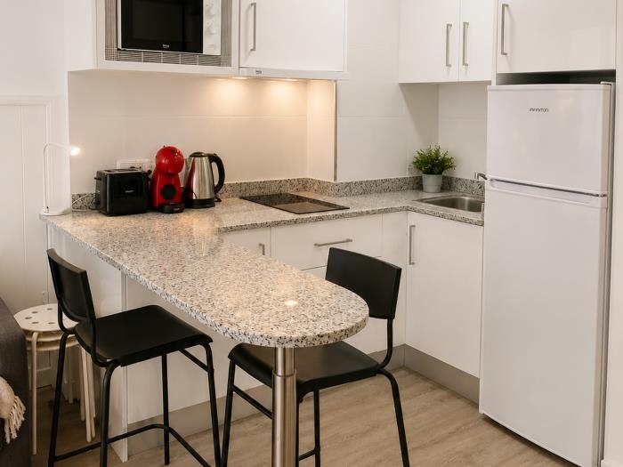 Cocina moderna equipada con barra desayunadora, cafetera y espacio funcional para una estancia cómod