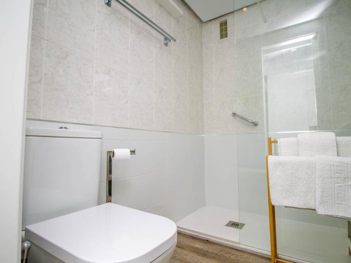 Baño moderno con ducha amplia, acabados elegantes y diseño funcional luminoso.