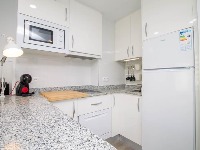 Cocina moderna equipada con microondas, cafetera y espacio funcional para una estancia cómoda.