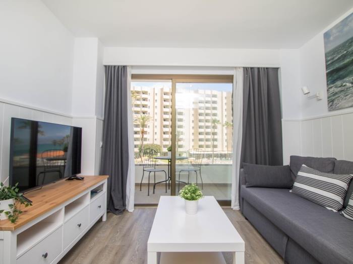 Salón moderno con Smart TV, terraza privada y ambiente luminoso cerca de la playa.