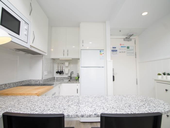 Cocina moderna equipada con barra desayunadora y espacio funcional para una estancia cómoda.