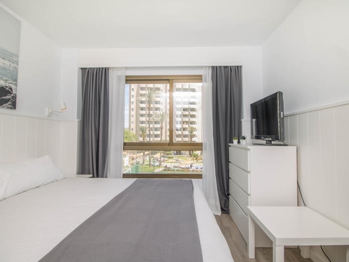 Dormitorio moderno y luminoso con Smart TV y ambiente relajante cerca de la playa.