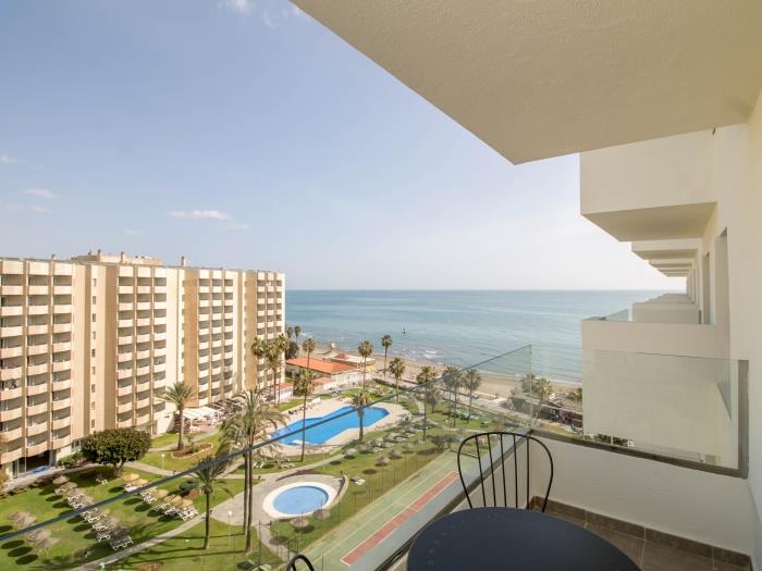 Terraza privada con vistas panorámicas al mar, jardines y piscina junto a la playa.