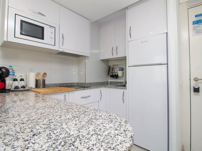 Cocina moderna equipada con barra desayunadora, microondas y espacio funcional.