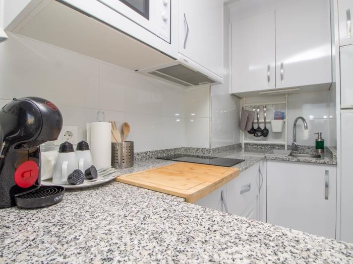 Cocina moderna equipada con cafetera, barra desayunadora y diseño funcional.
