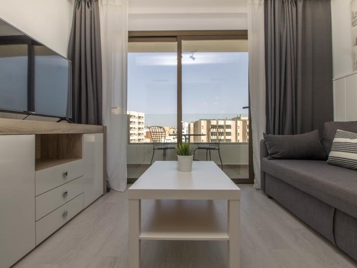 Salón moderno con Smart TV, terraza privada y ambiente luminoso cerca de la playa.