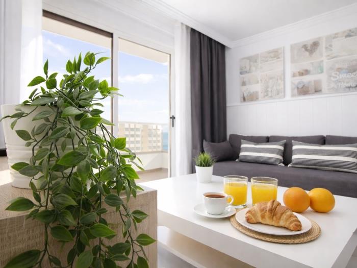 Salón moderno con terraza privada, luz natural y zona de desayuno cerca de la playa.