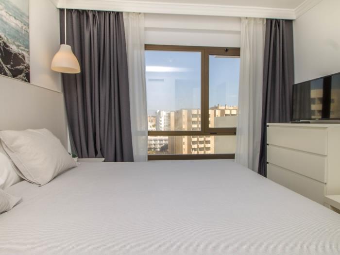 Dormitorio moderno y luminoso con Smart TV y ambiente relajante cerca de la playa.