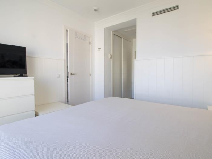 Dormitorio moderno y luminoso con Smart TV, diseño minimalista y ambiente relajante.
