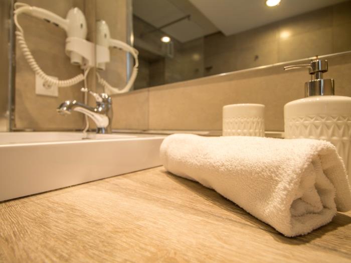Baño moderno con ducha amplia, lavadora y acabados elegantes para mayor comodidad.