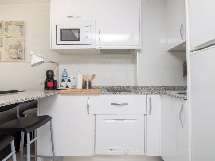 Cocina moderna equipada con microondas, cafetera y diseño funcional para una estancia cómoda.
