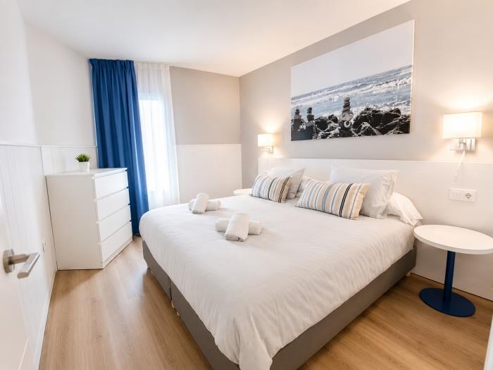 Dormitorio moderno y luminoso con cama doble, aire acondicionado y ambiente acogedor para descansar.