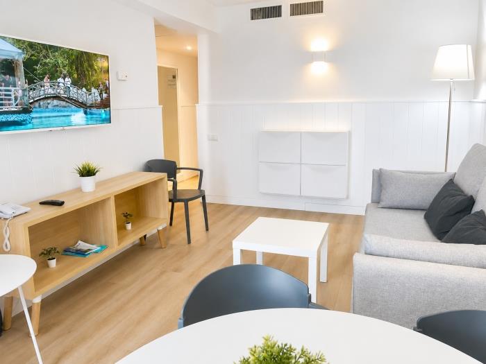Salón moderno con Smart TV, decoración elegante y ambiente luminoso cerca de la playa.