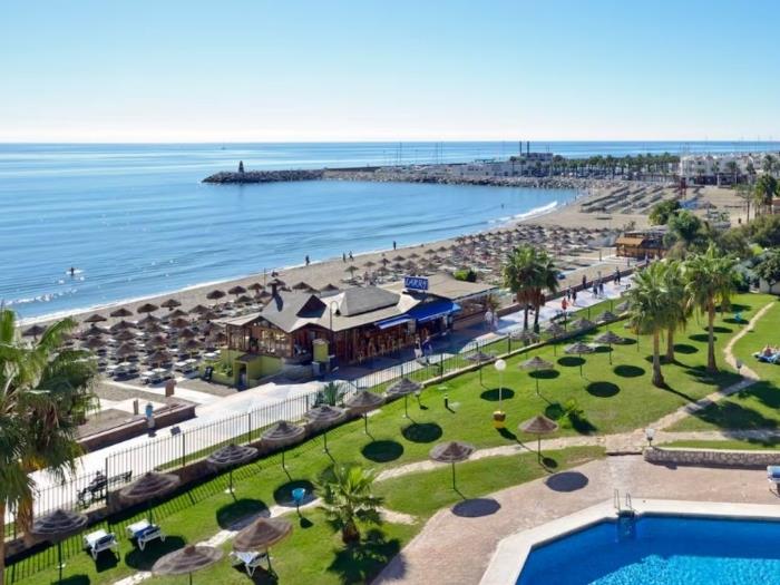 Apartamento en primera línea de playa con vistas al mar, jardines y zona de piscina.