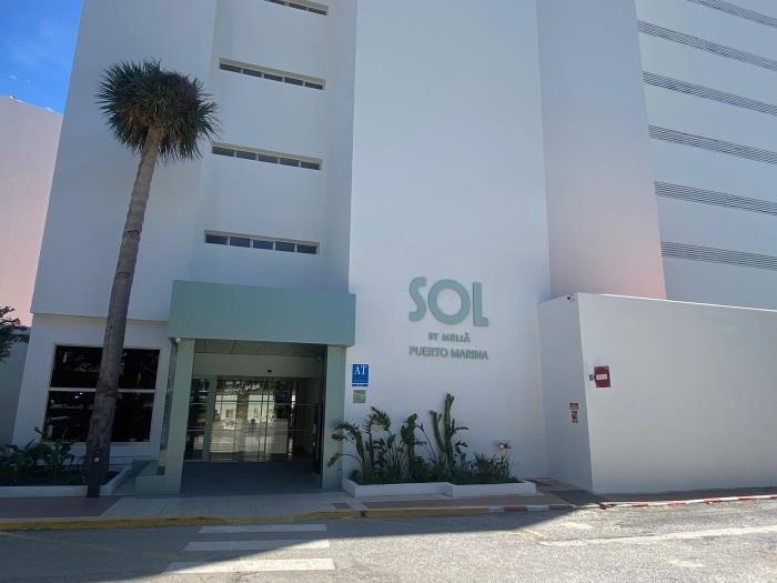 Complejo moderno en primera línea de playa con palmeras y ubicación privilegiada junto al mar.