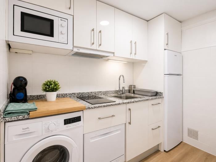 Cocina moderna equipada con microondas, lavadora y espacio funcional para una estancia cómoda.