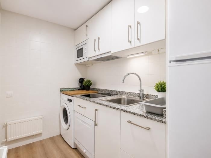Cocina moderna equipada con lavadora, microondas y espacio funcional para una estancia cómoda.