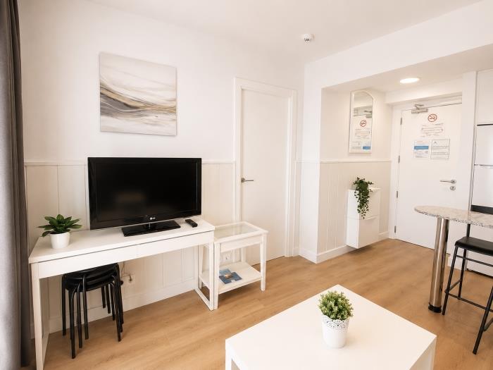 Salón moderno con Smart TV, decoración elegante y ambiente luminoso cerca de la playa.