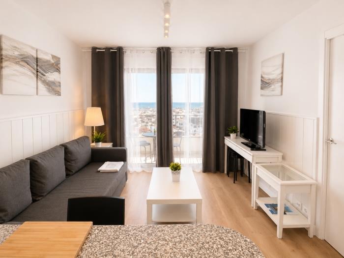 Salón moderno con vistas al mar, Smart TV y ambiente luminoso cerca de la playa.