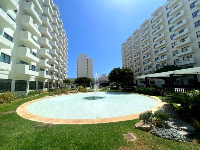 Residencial moderno con jardines, fuente central y ambiente tranquilo cerca de la playa.