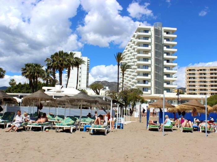 Playa junto al mar con noria, palmeras y ambiente turístico ideal para disfrutar del sol.