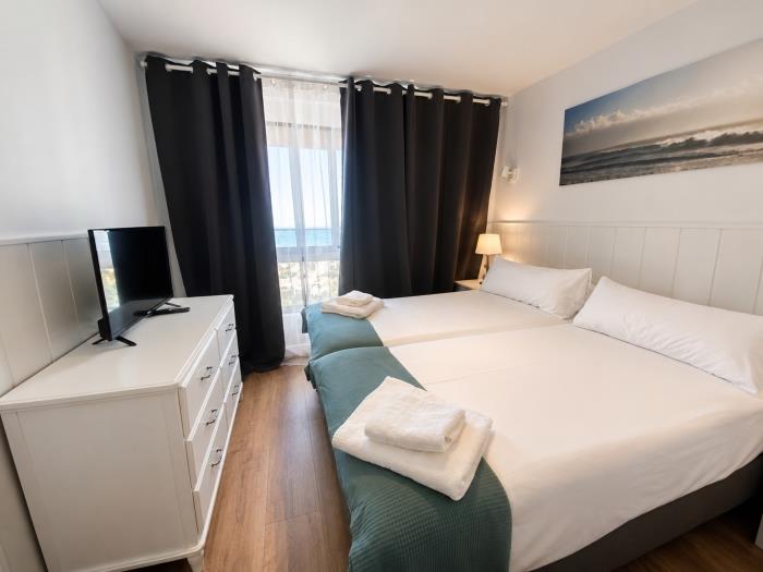 Dormitorio moderno y luminoso con camas individuales, vistas al mar y ambiente relajante.