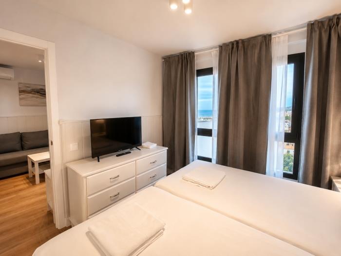 Dormitorio moderno y luminoso con camas individuales, vistas al mar y ambiente relajante.