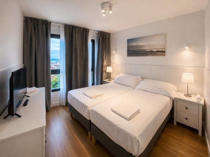 Dormitorio moderno y luminoso con camas individuales, vistas al mar y ambiente relajante.