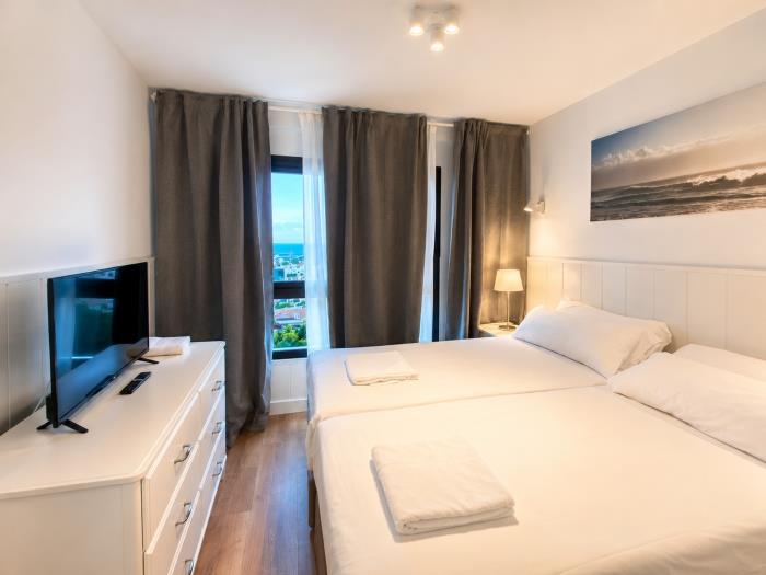 Dormitorio moderno y luminoso con camas individuales, vistas al mar y ambiente relajante.