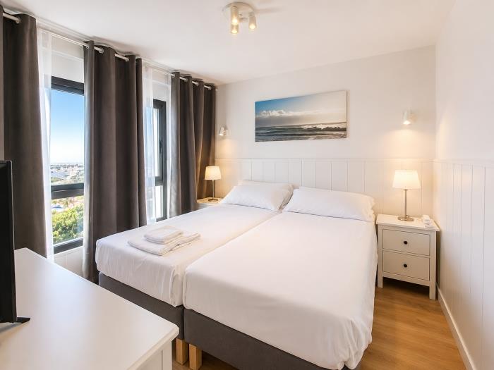 Dormitorio moderno y luminoso con camas individuales, vistas al mar y ambiente relajante.