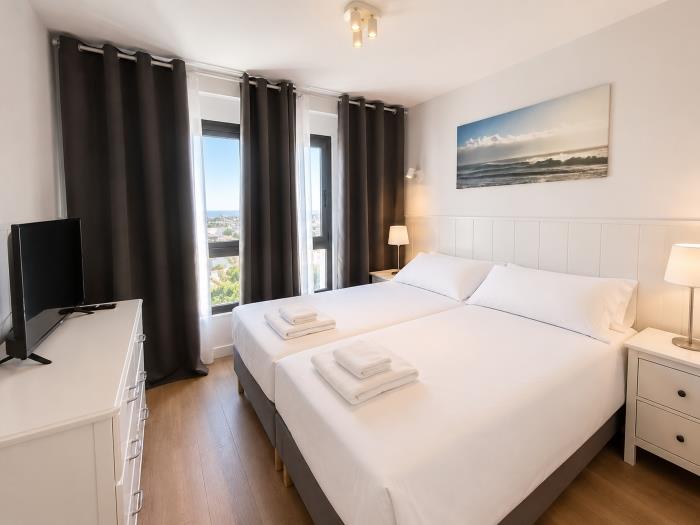 Dormitorio moderno y luminoso con camas individuales, vistas al mar y ambiente relajante.