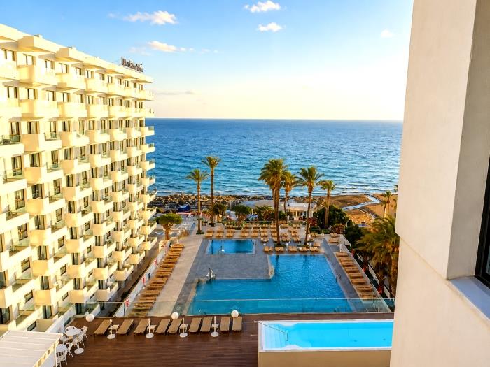 Beachfront apartment with sea views, pool area and palm trees for relaxing holiday stays.
