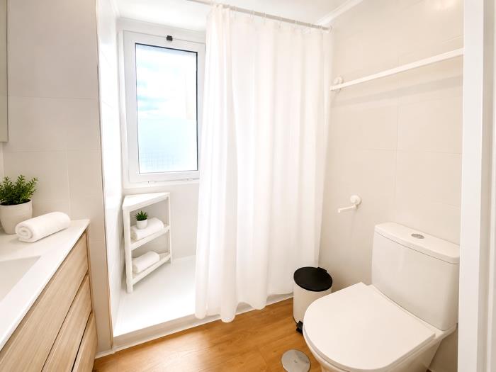 Modern bathroom with shower, natural light and functional design for comfortable holiday stays.